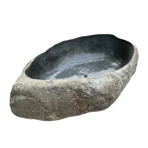 Handcrafted natural river stone bathtub with polished interior and raw stone exterior